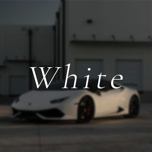 A white sports car is parked in front of a building that says white