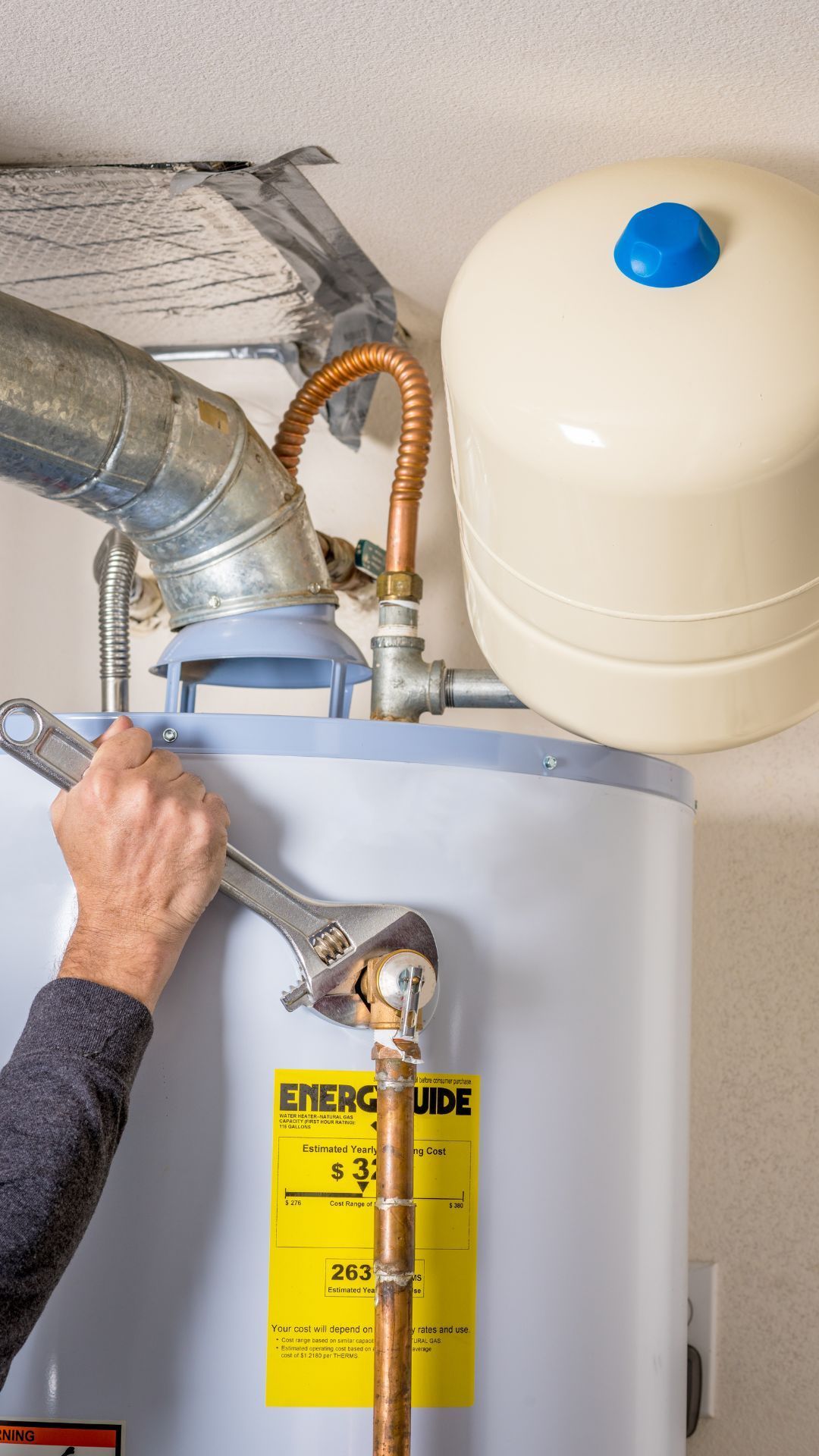 A man is fixing a water heater with a wrench.