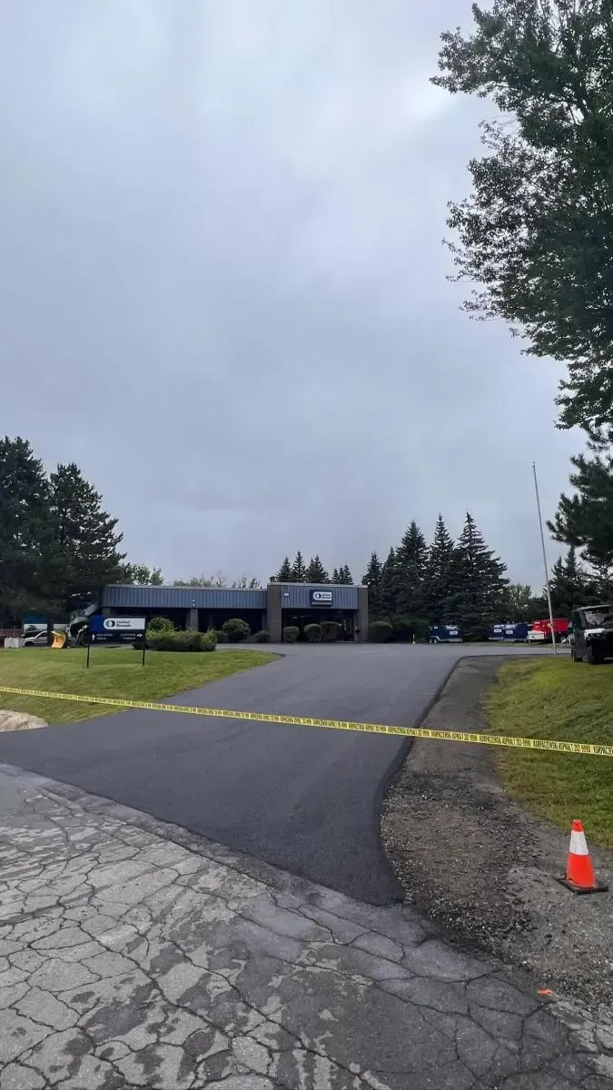 Building with caution tape across driveway, under overcast sky.