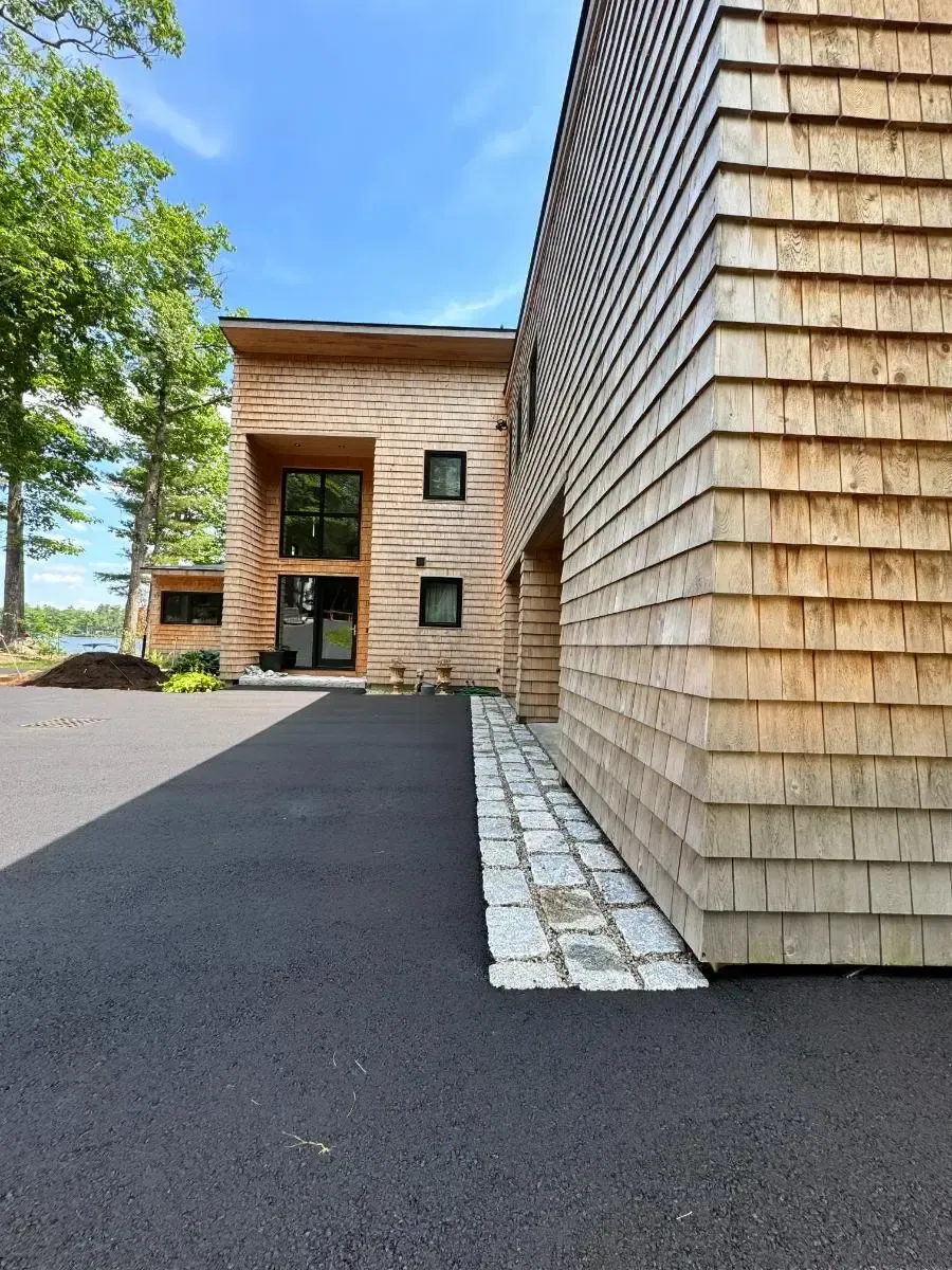 Paver pathway curving from driveway to house with side lawn and gravel border.