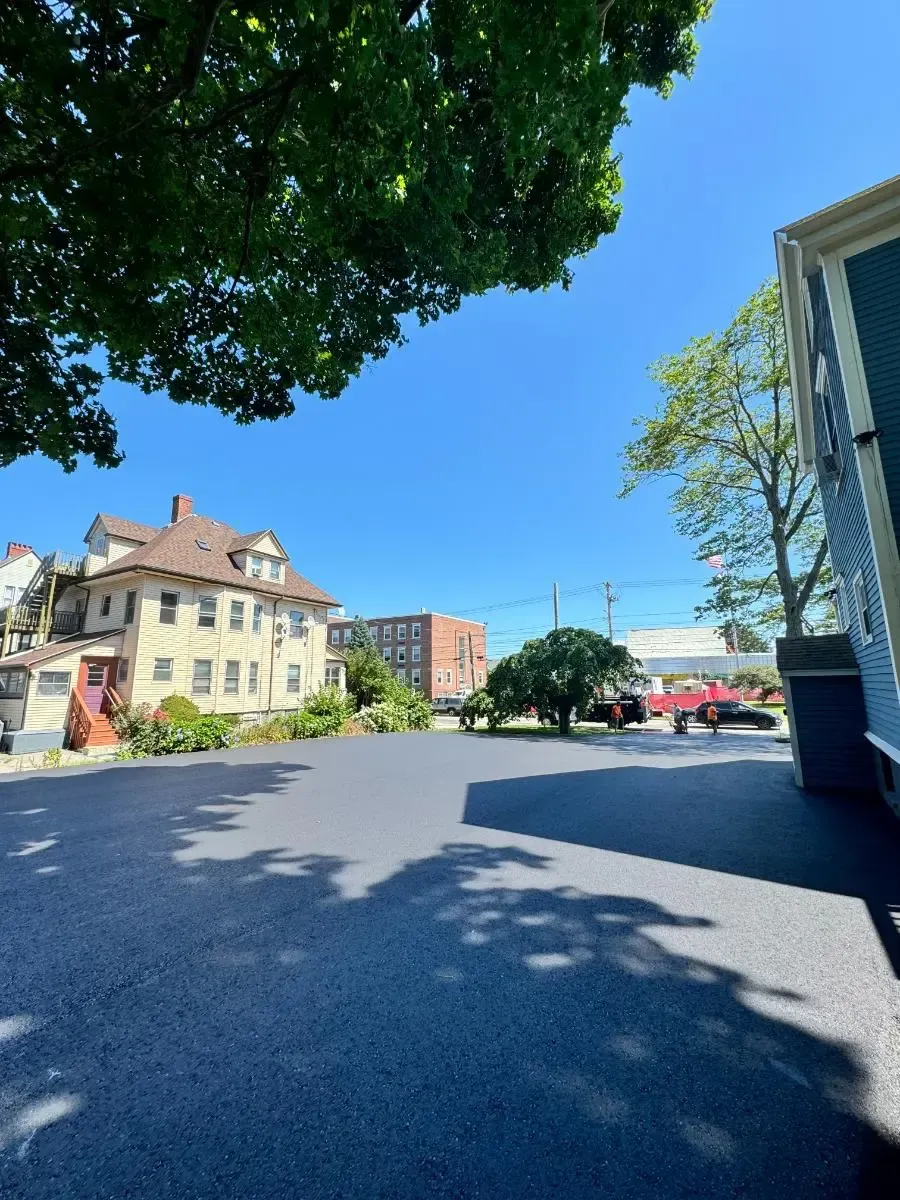 Large asphalt parking lot in front of buildings on a sunny day.