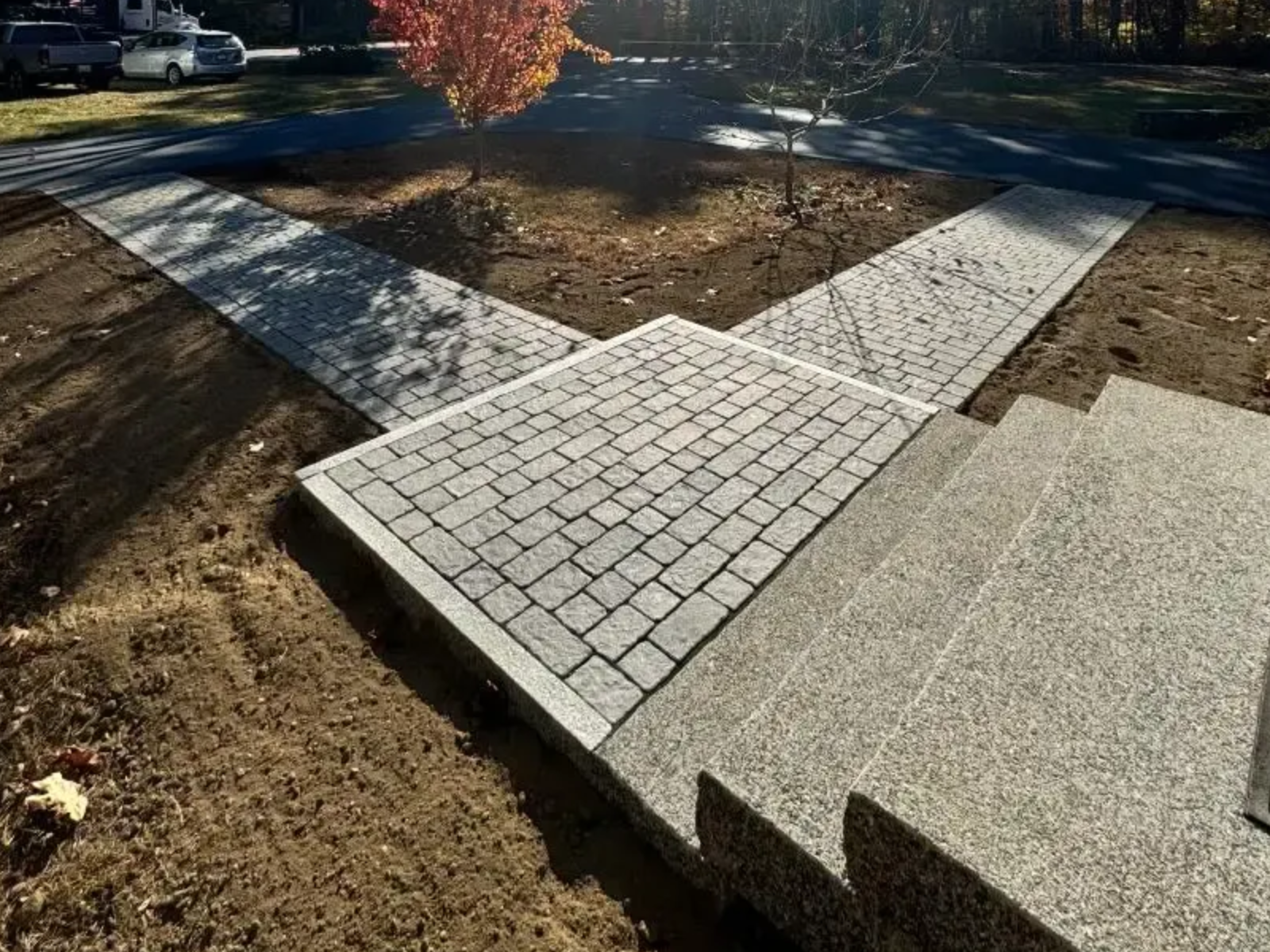 Brick pathways converge at a concrete landing and steps. Brown and gray tones are dominant.
