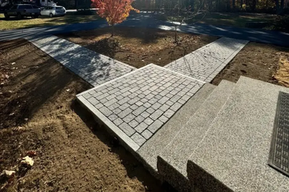 Brick pathways converge at a concrete landing and steps. Brown and gray tones are dominant.