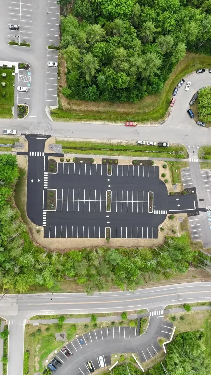 Construction workers paving a driveway at a modern wood-sided house.