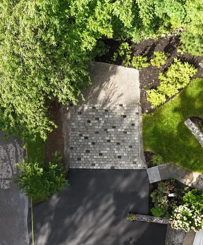 Stone path leading to a road and trees with fall foliage; sunny day.
