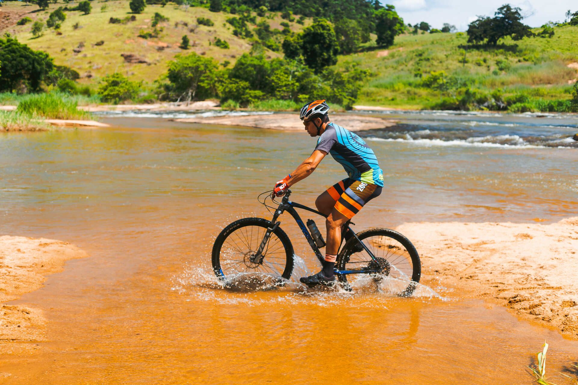Um homem está andando de bicicleta por um rio.