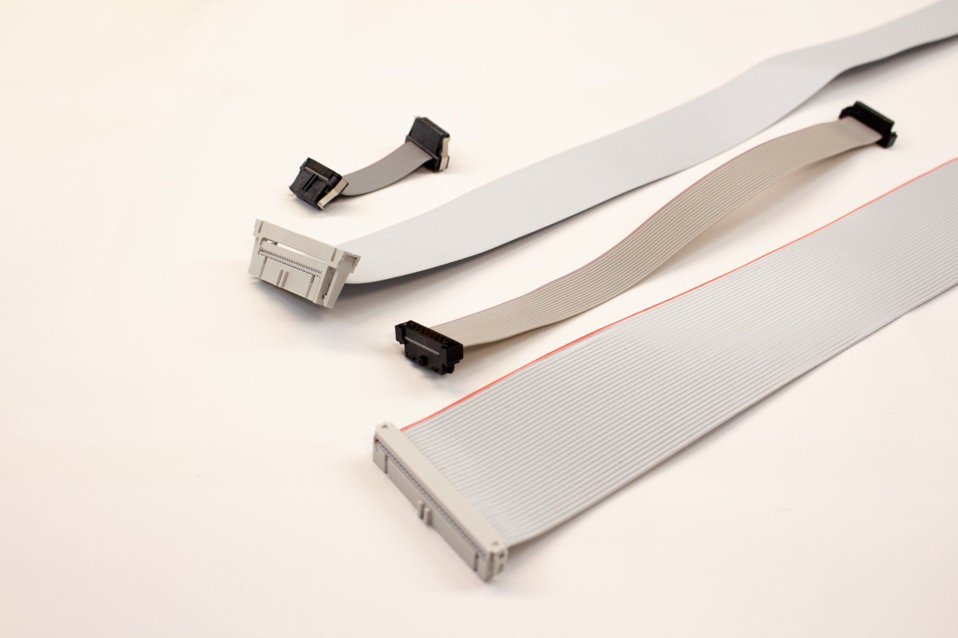 Three different types of wires are laying on a white surface