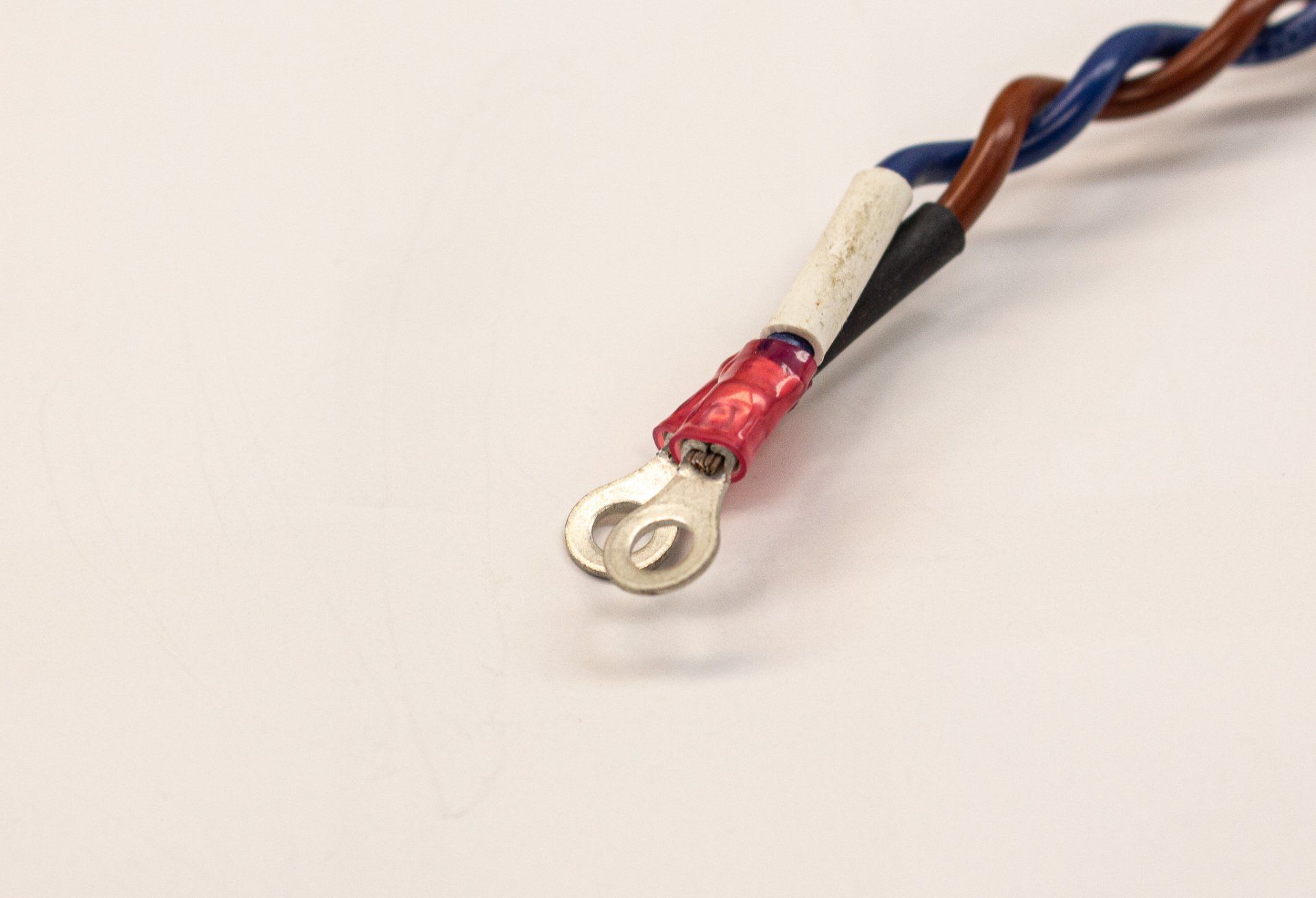 A close up of a wire with a red connector on a white surface.