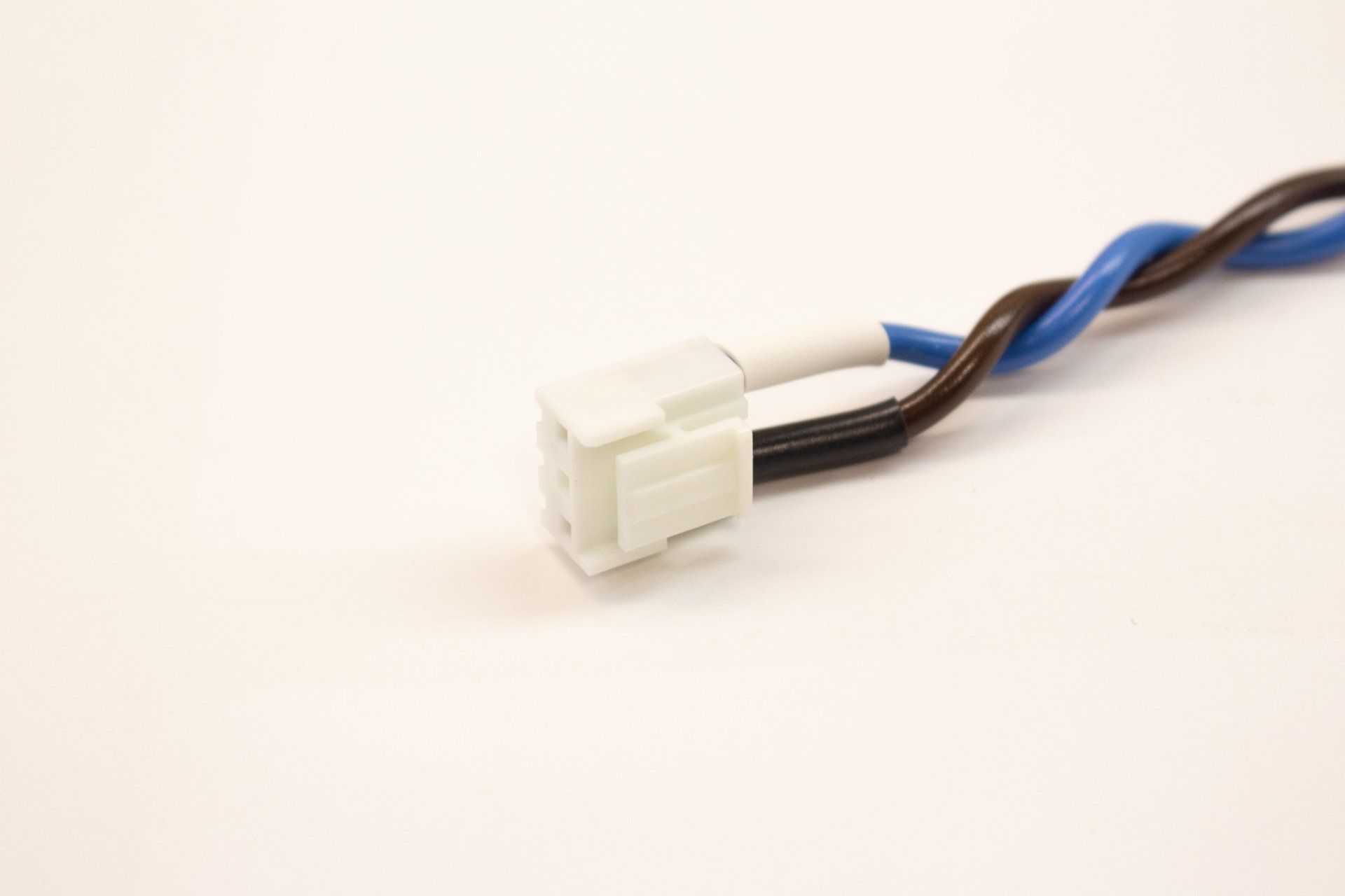 A close up of a wire with a white connector on a white surface.