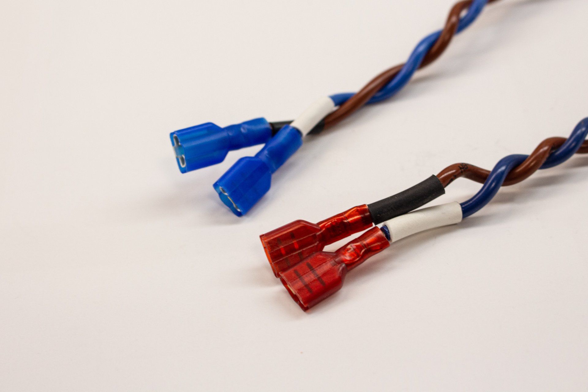 Two wires with blue and red connectors on a white surface