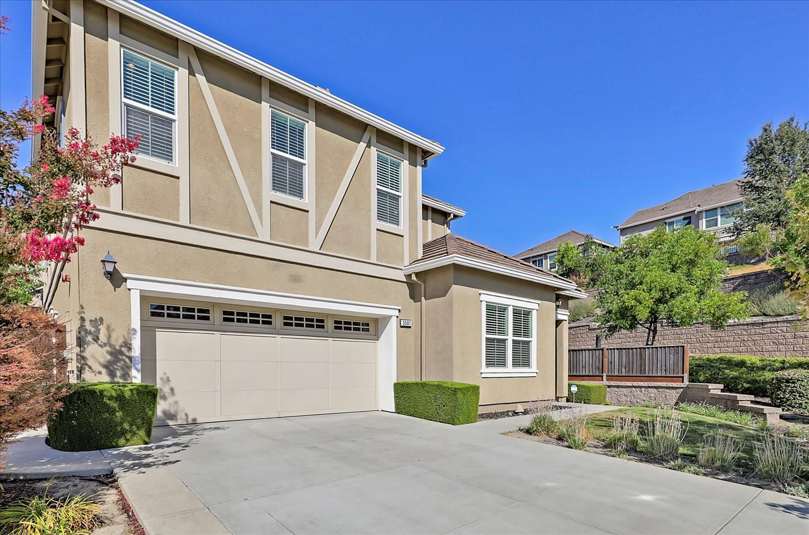 Two-story beige house with a garage, white trim, and a concrete driveway under a blue sky in Dublin Ranch CA