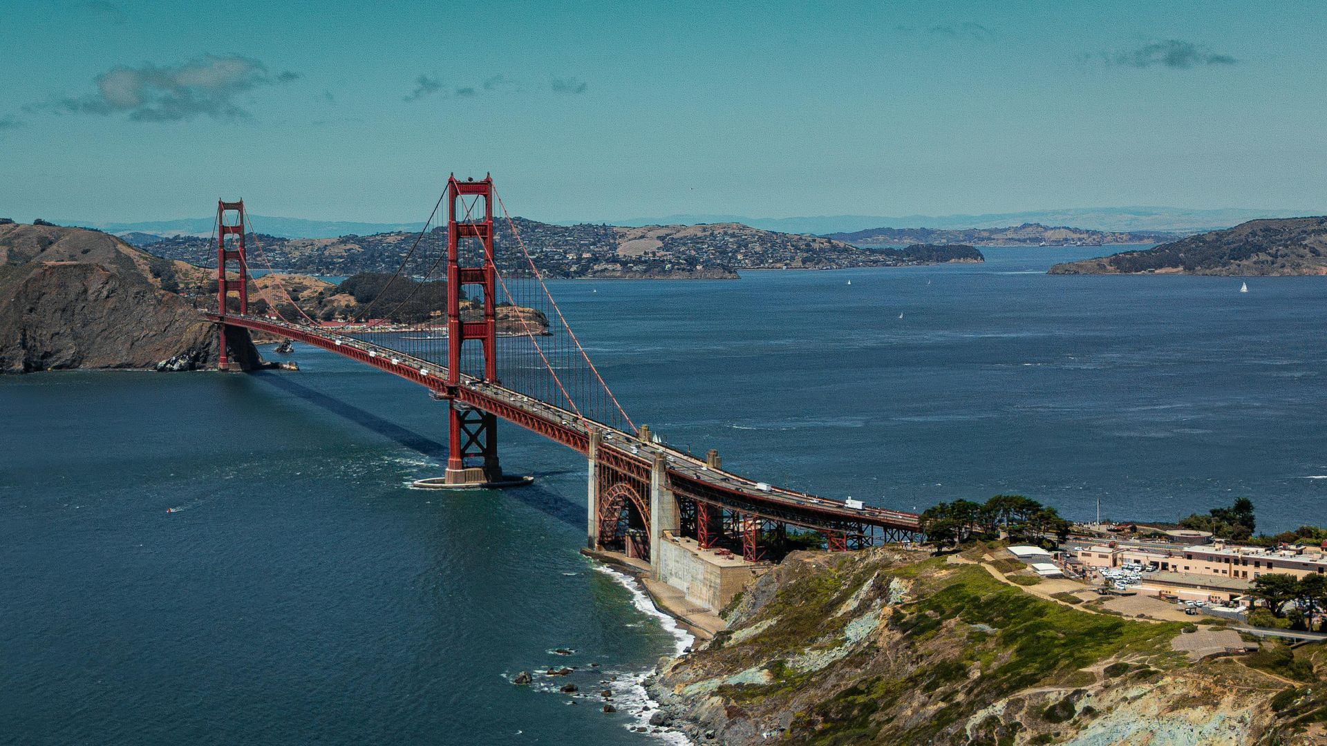 Golden Gate Bridge in San Francisco, spanning water; red towers, cars on the road, sunny day.