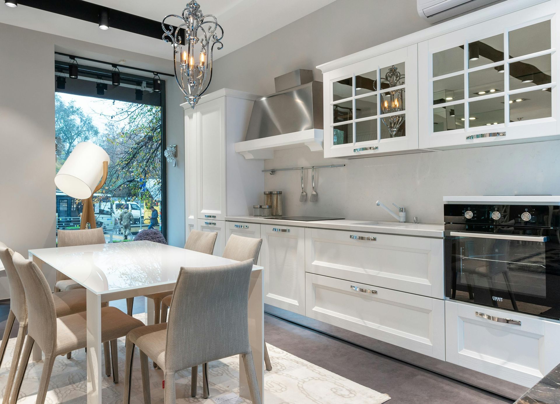 White kitchen with dining table, cabinets, oven, and a window to the outside.
