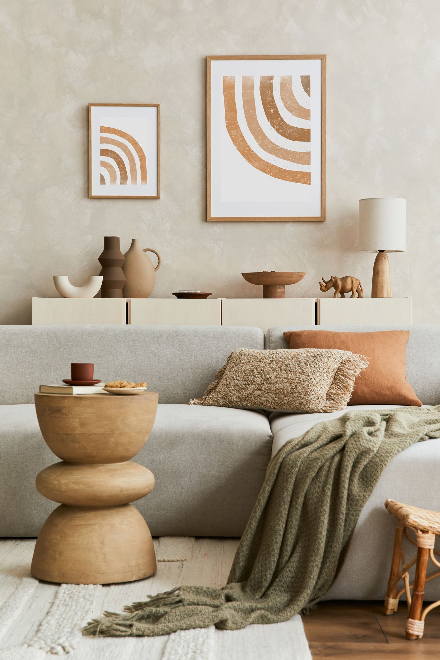 Bohemian living room with neutral tones: sofa, art, side table, throw blanket, and decor.
