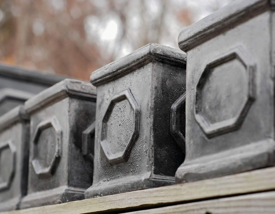 Close-up of a series of dark, decorative concrete posts with octagonal designs on a wooden structure.