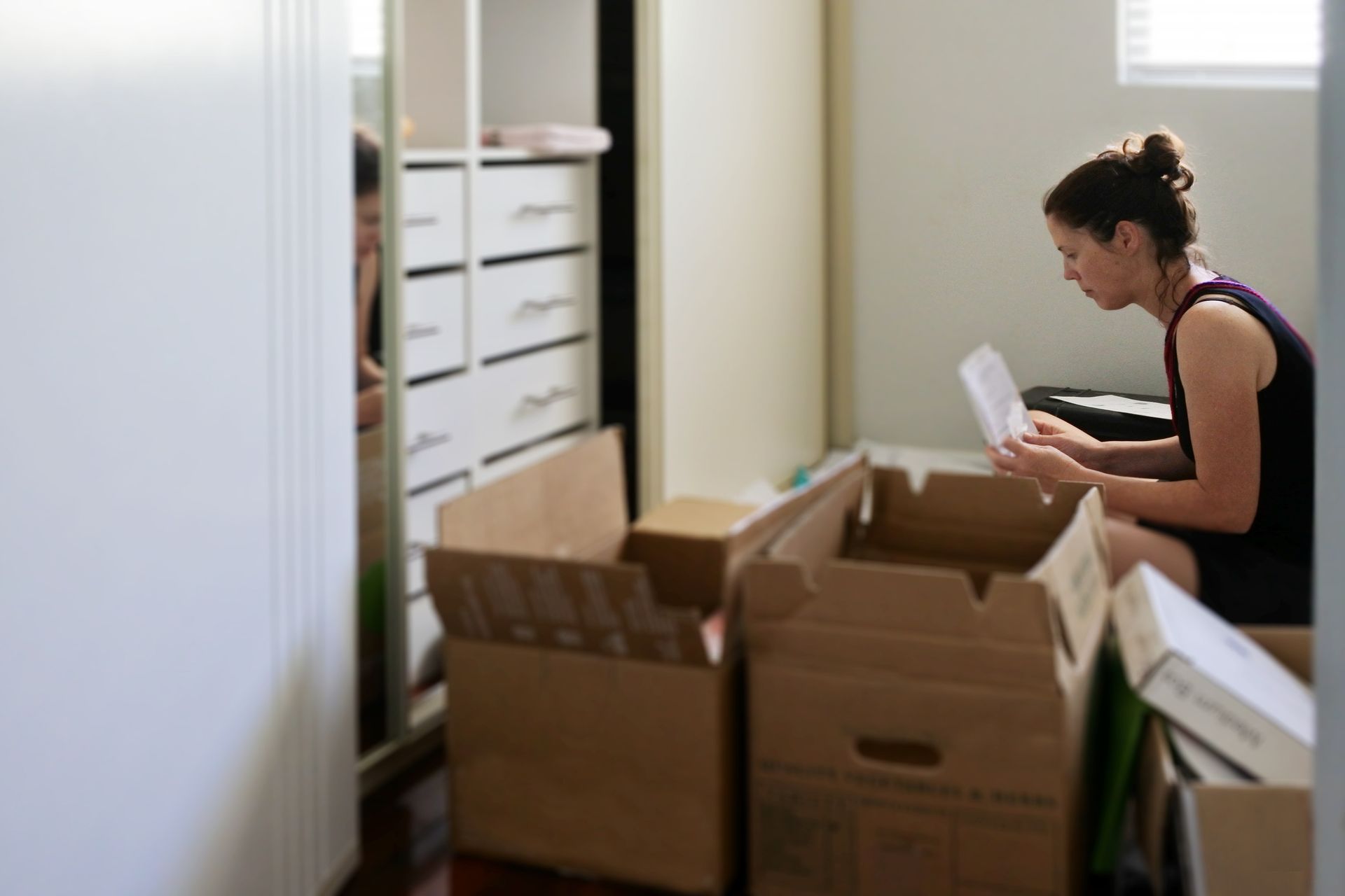 A room filled with boxes , a broom , a spray bottle and a ladder.