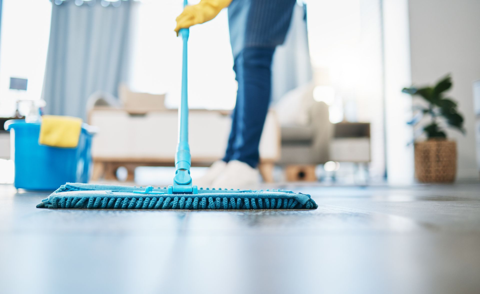 A person is cleaning the floor with a mop in a living room.