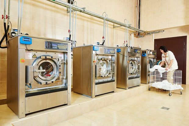 A woman is standing in front of a row of washing machines