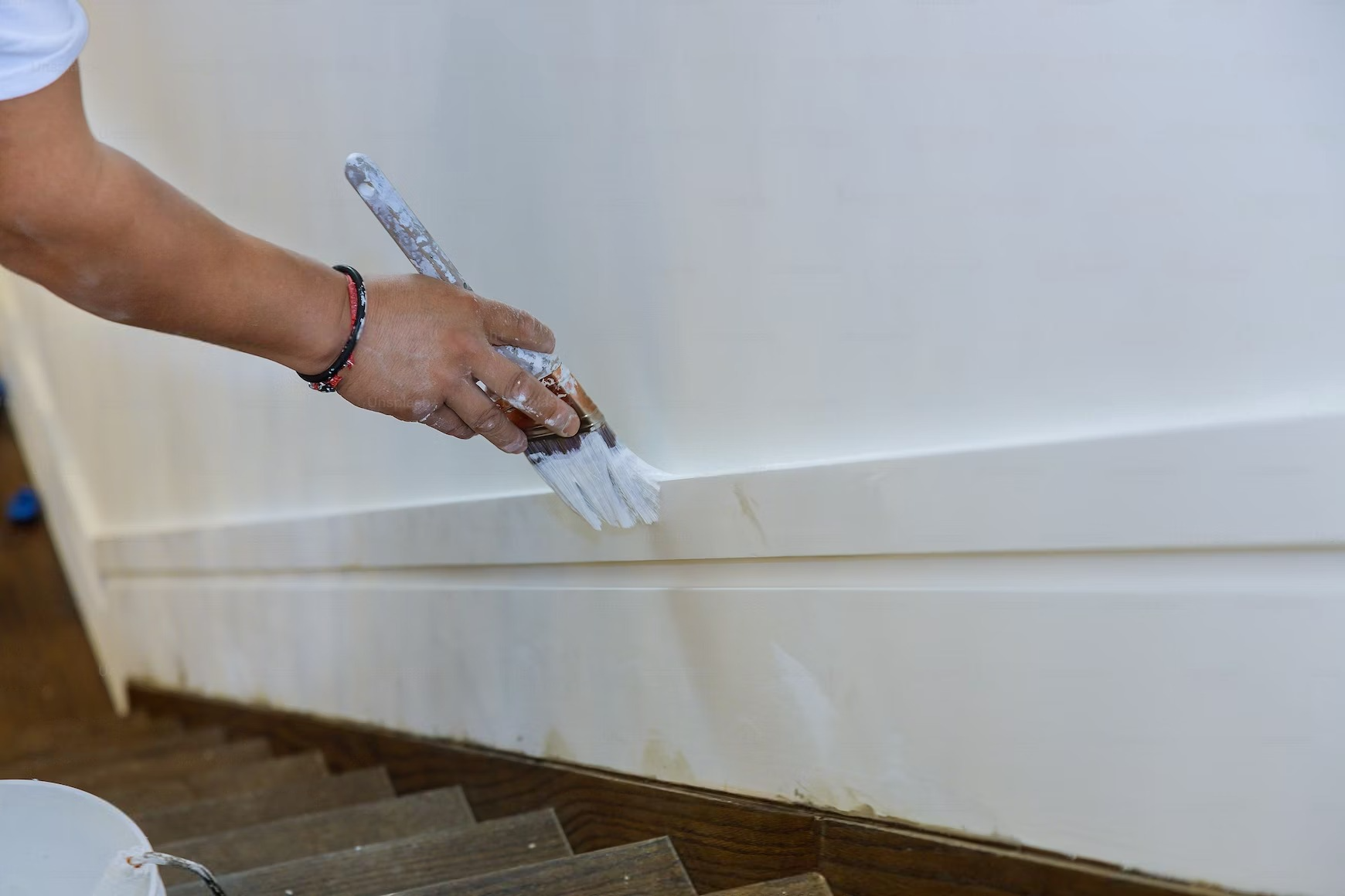 A person is painting a wall with a brush.