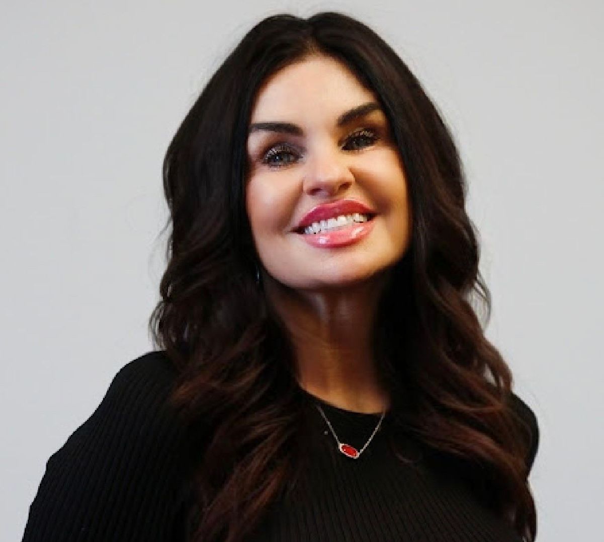 A brown-haired woman in a black shirt smiling.