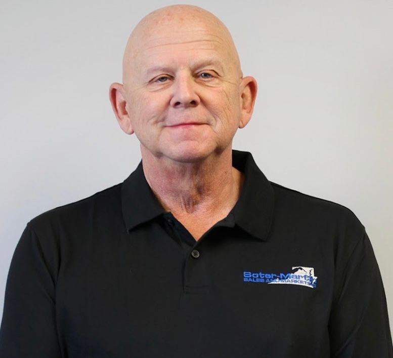 A bald man wearing a black shirt with a blue logo on the front