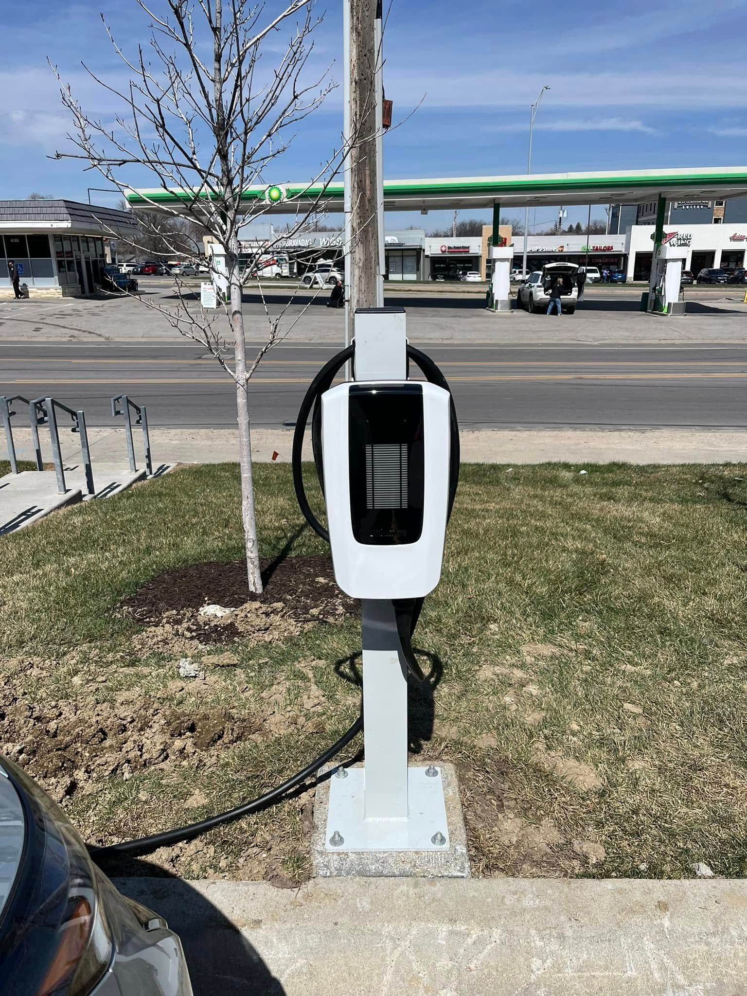 A car is being charged at a charging station on the side of the road.