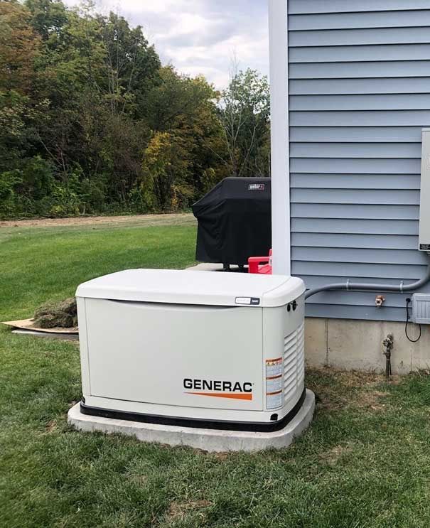 A generator is sitting in the grass next to a house.
