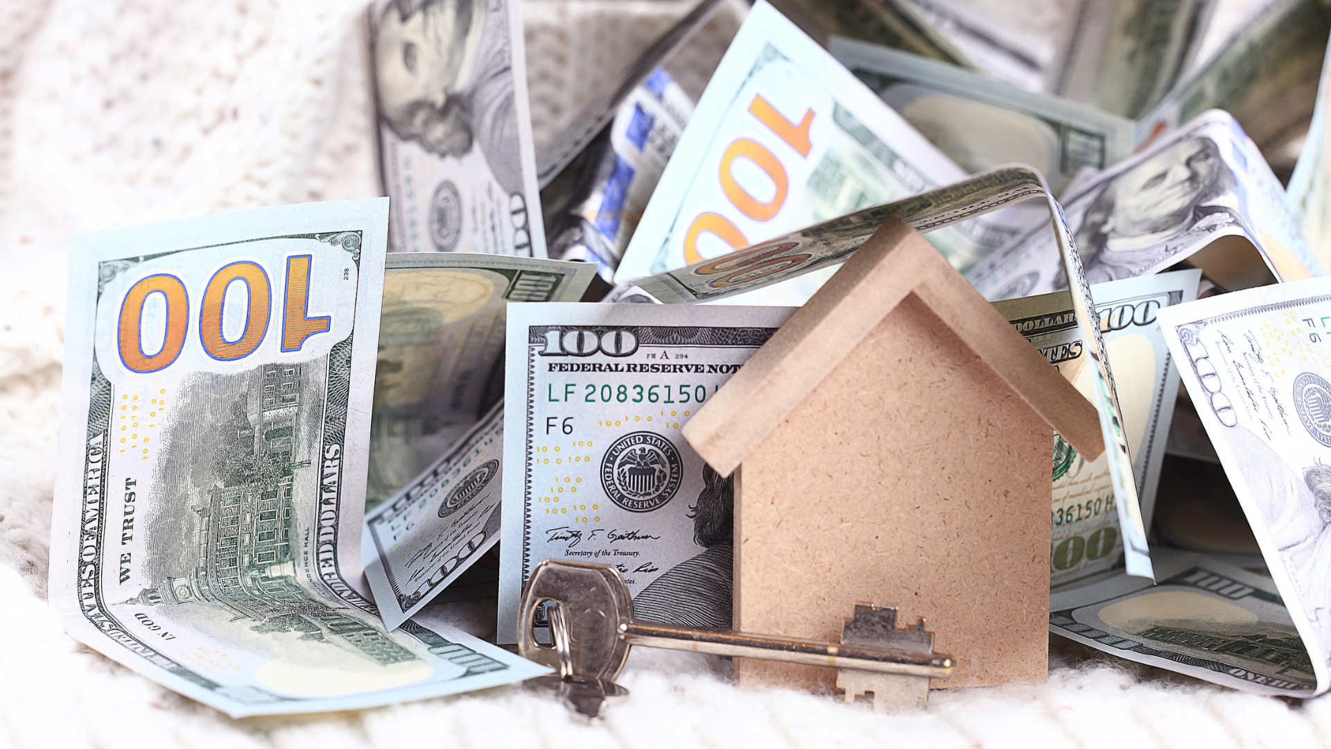 A model house is sitting on top of a pile of money.