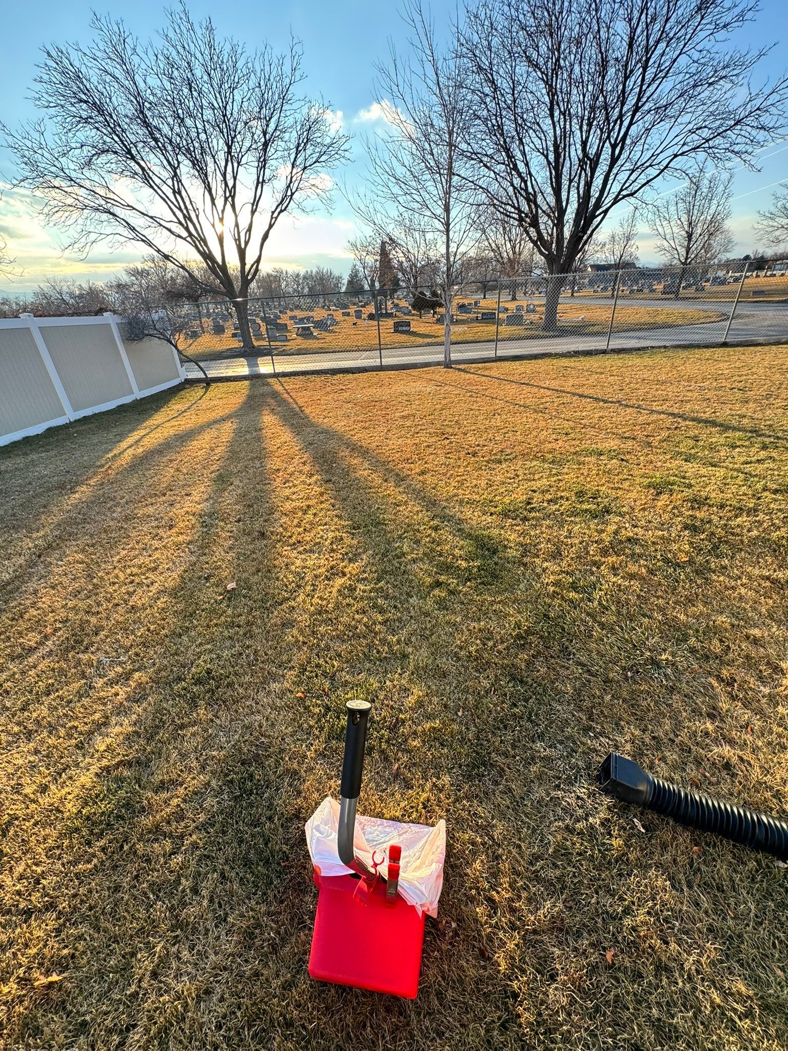 A red bucket and a shovel are sitting on the ground in a field.
