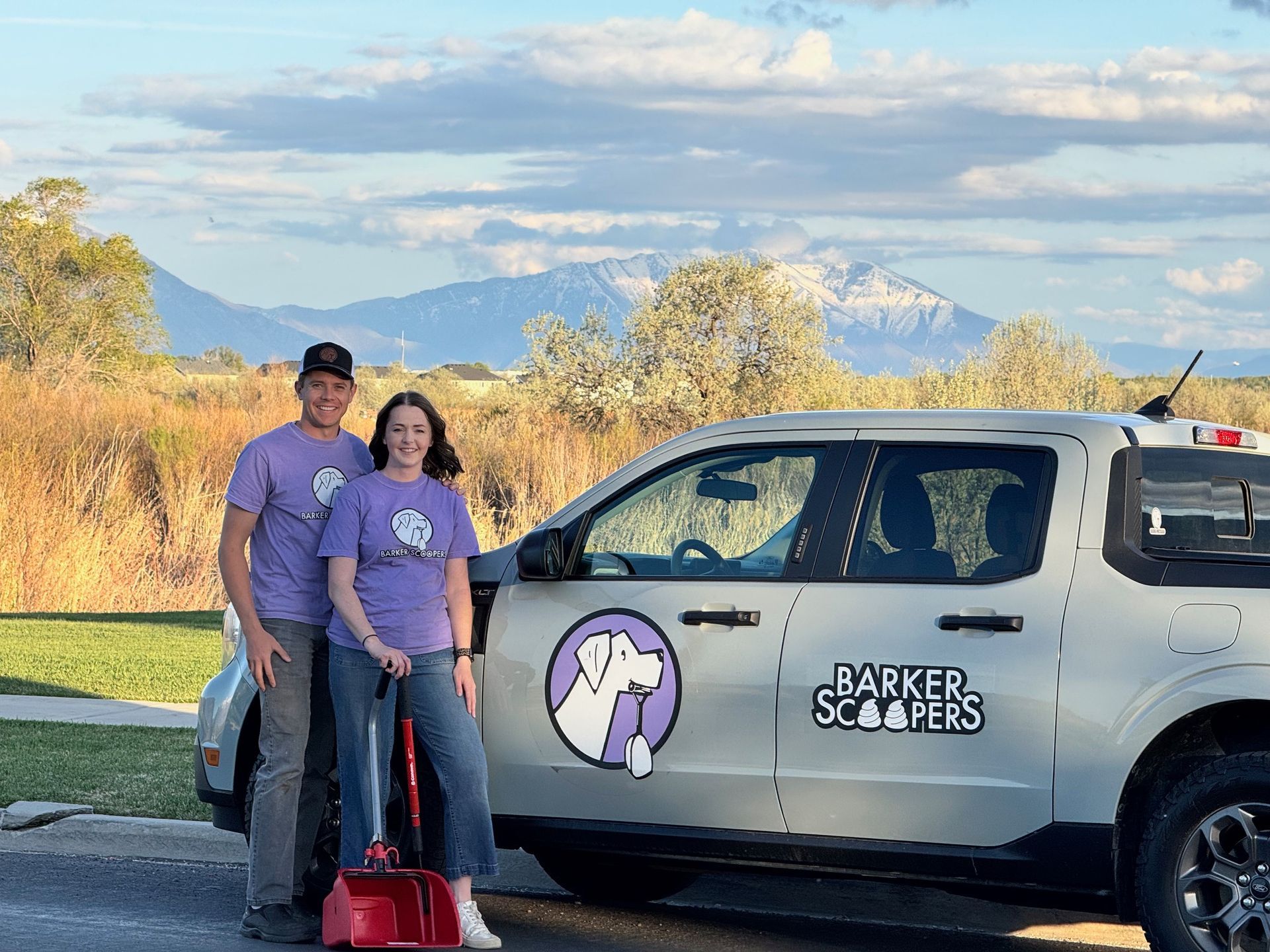 A family is standing in front of a truck holding snow shovels.