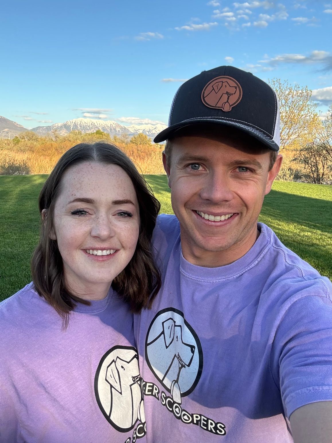 A man and a woman wearing purple shirts and hats are smiling for a picture.