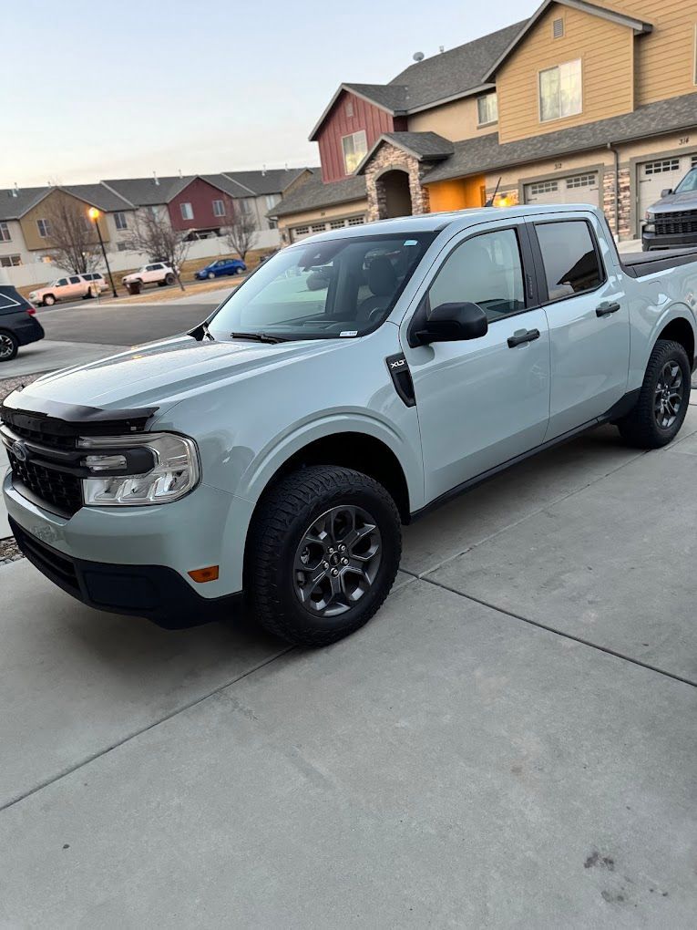A white truck is parked in a driveway in front of a house.