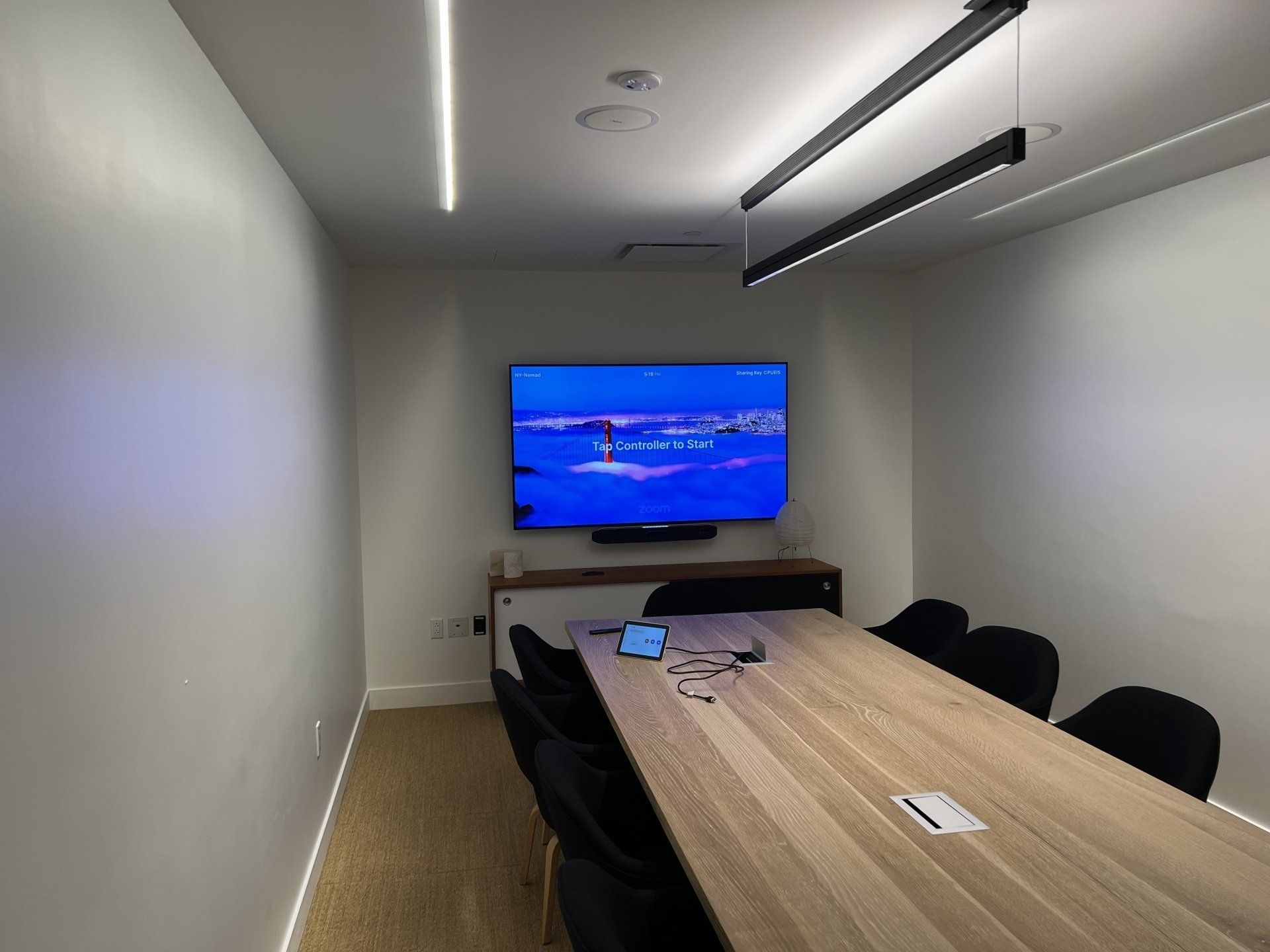 A conference room with a long table and chairs and a flat screen tv on the wall