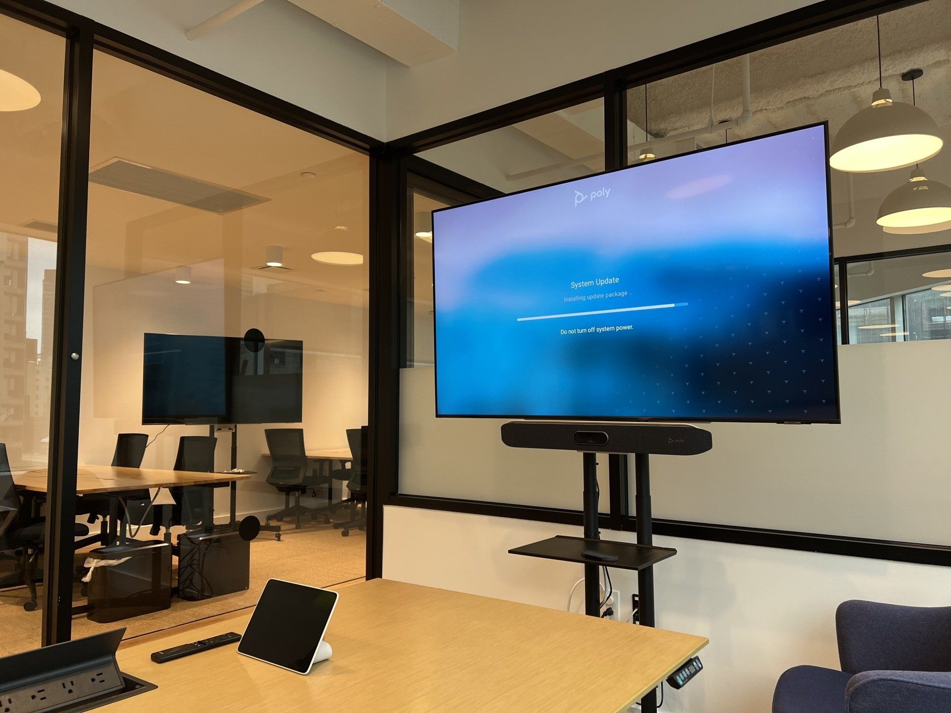 A conference room with a large flat screen tv on a stand