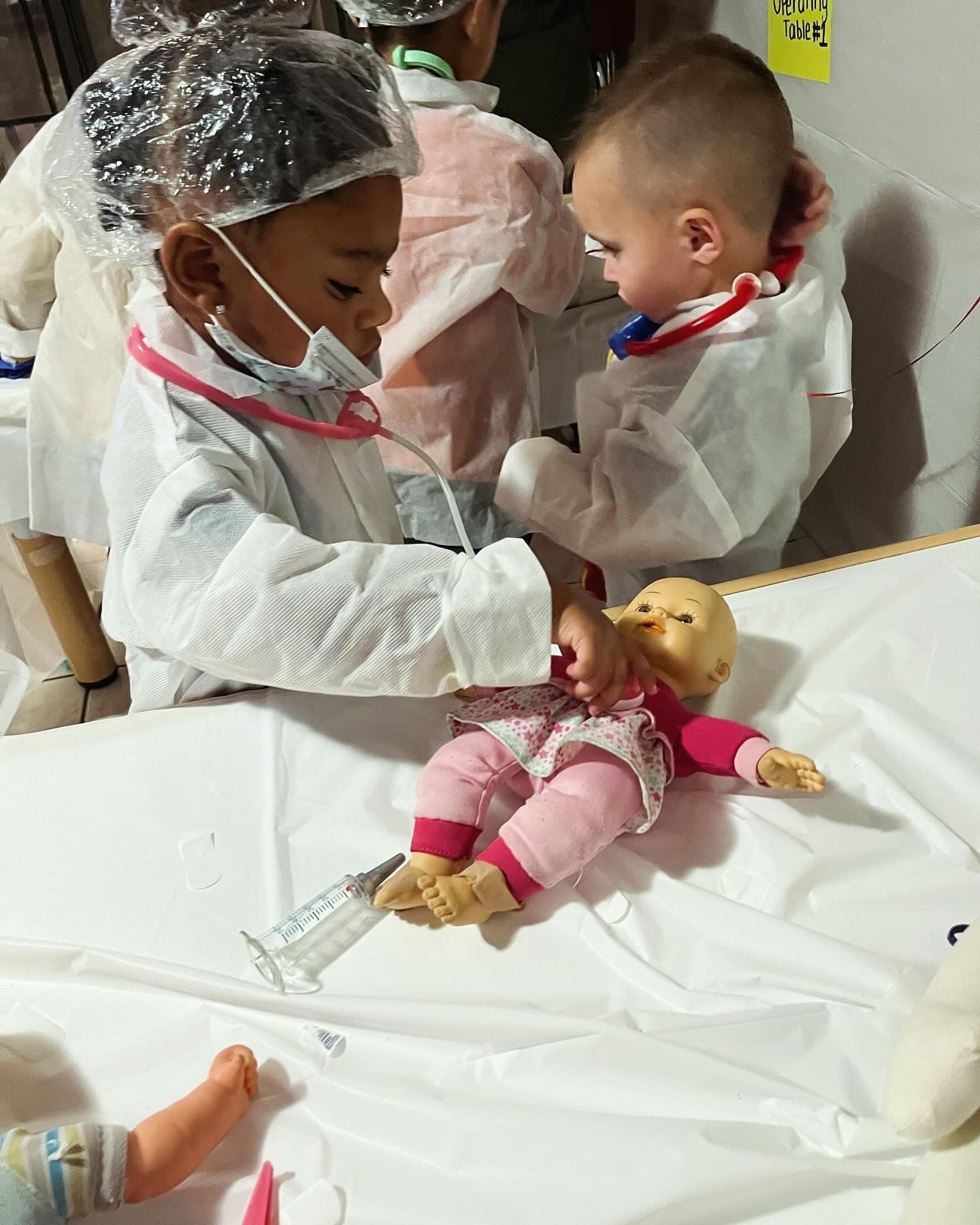 A little girl is playing doctor with a doll