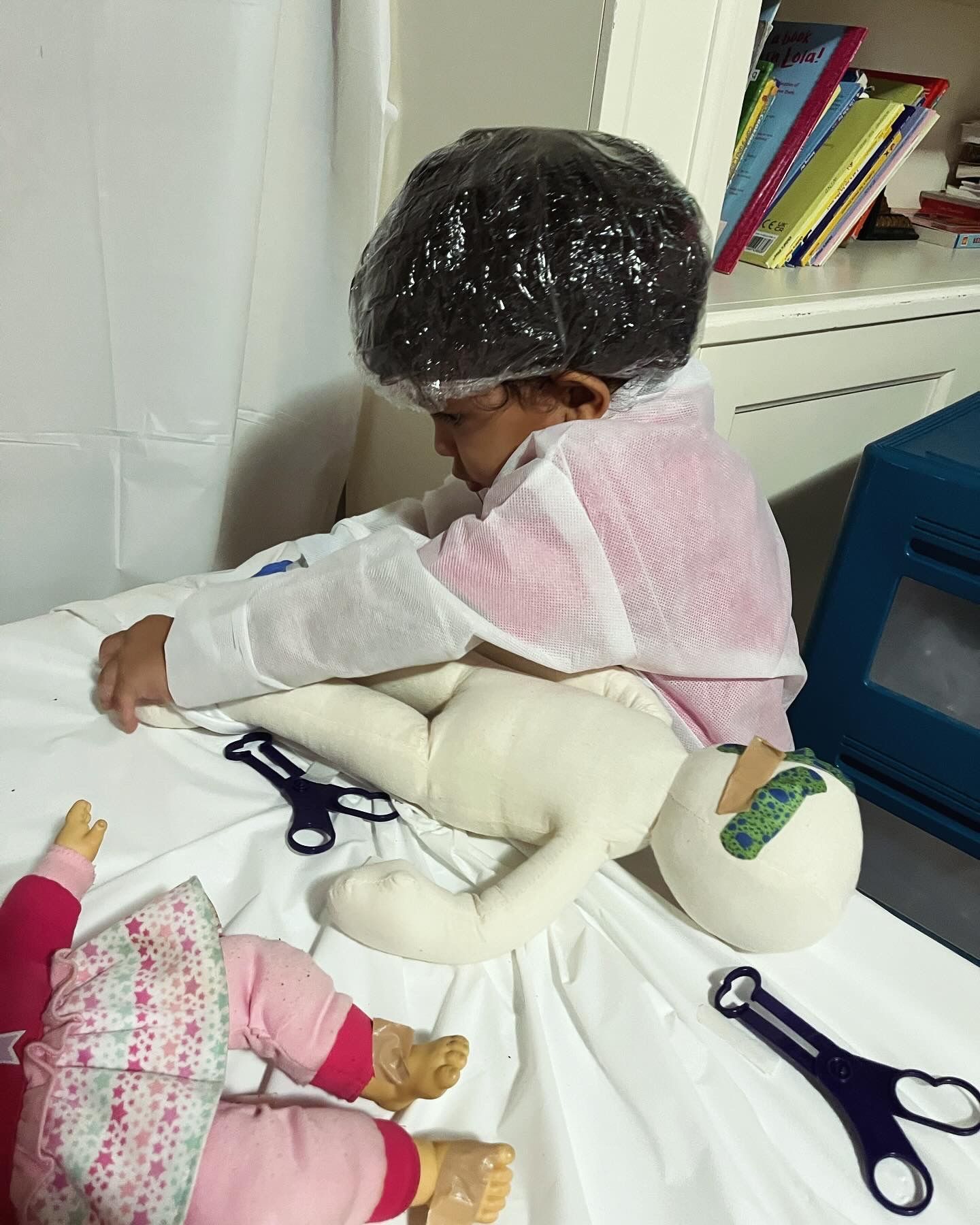 A little girl is playing with a doll on a bed