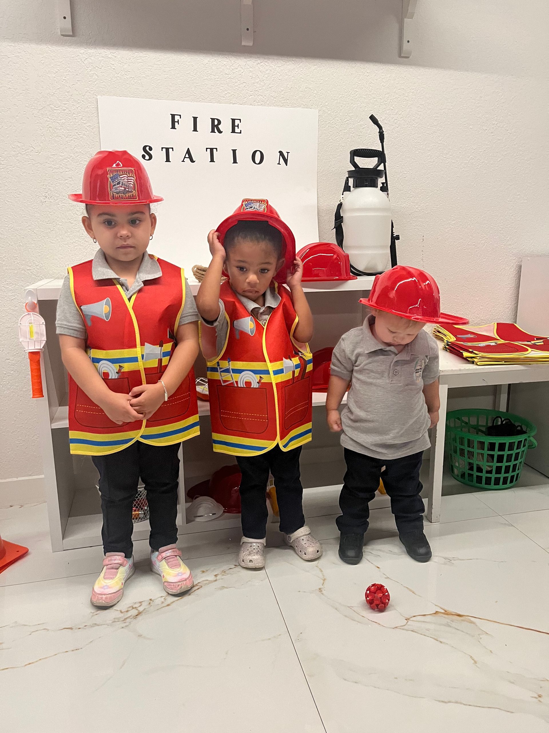 Three little boys dressed as firefighters are standing next to each other in a room.