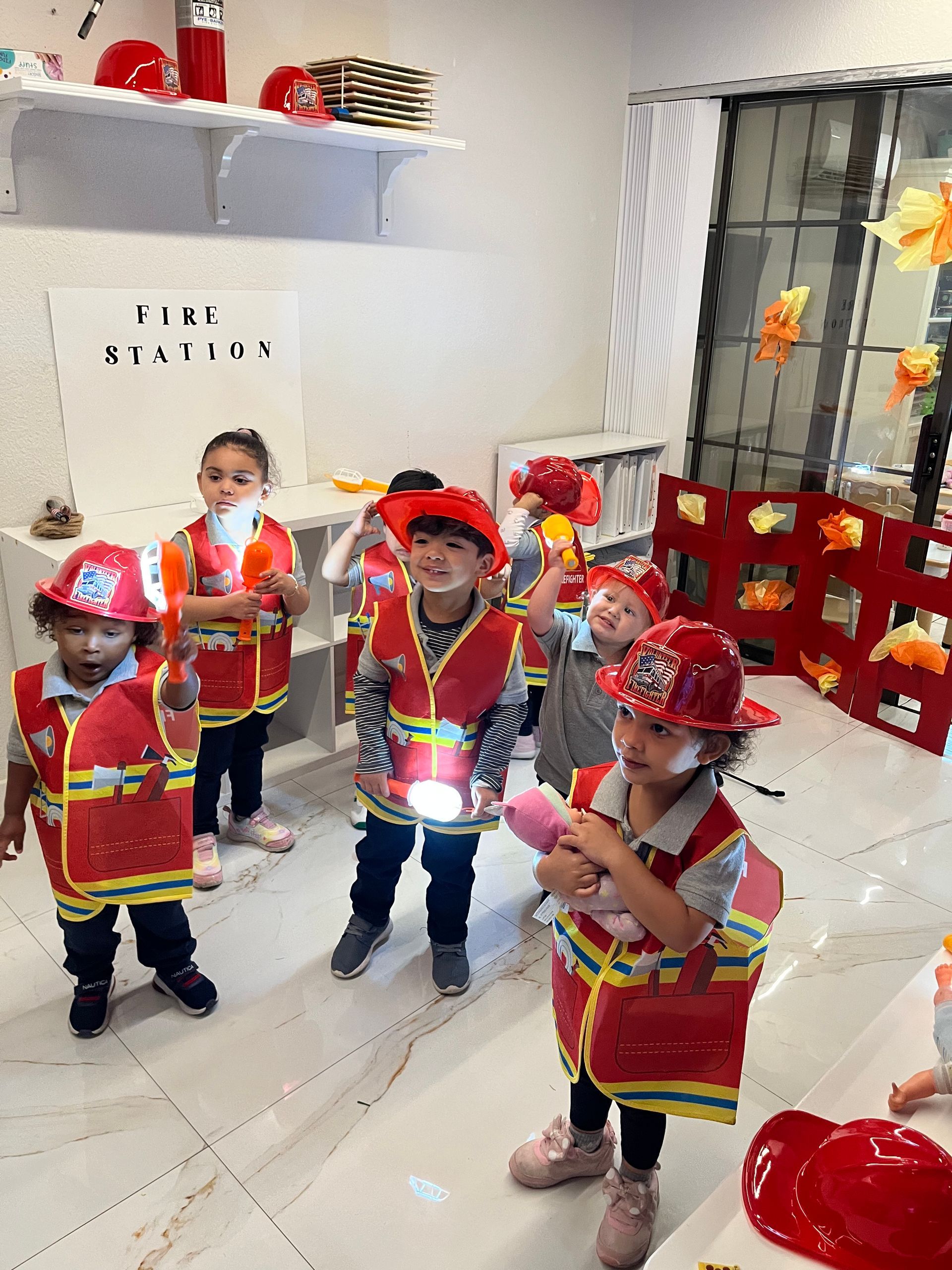 A group of children dressed in firefighter costumes are standing in a room.