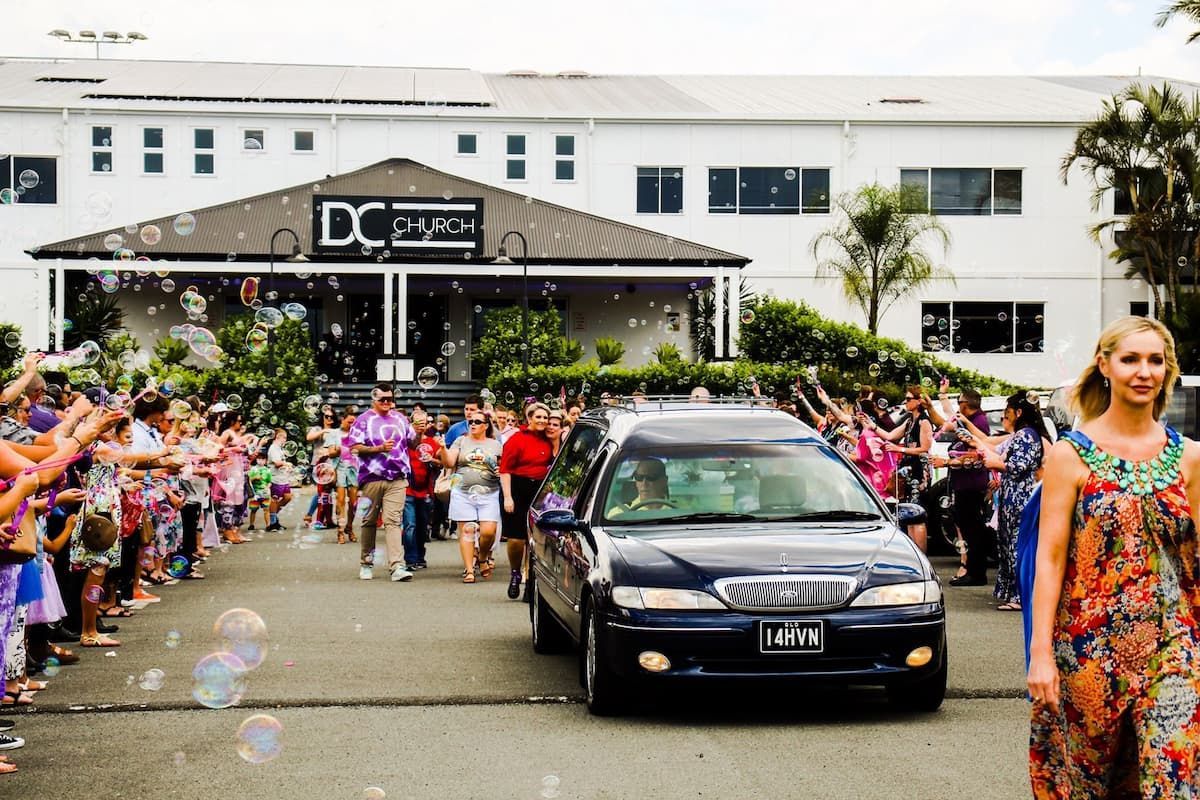 A woman walking in front of a funeral car - Funeral Services in Upper Coomera, QLD