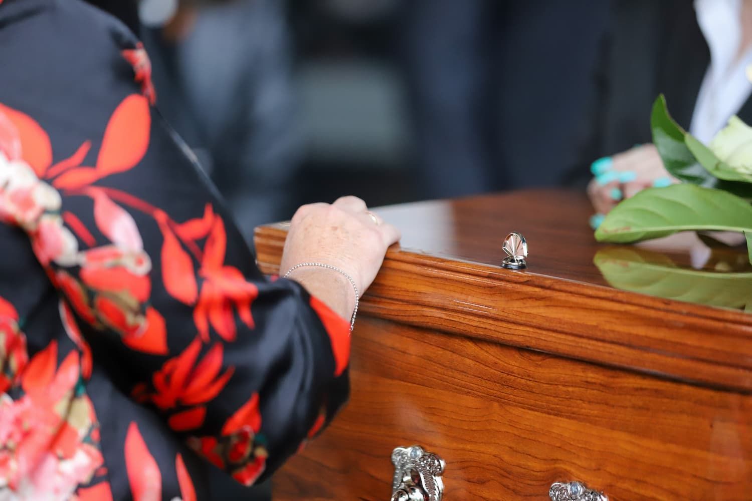 A woman in a red and black floral dress looks at her reflection in a mirror - Funeral Services in Upper Coomera, QLD