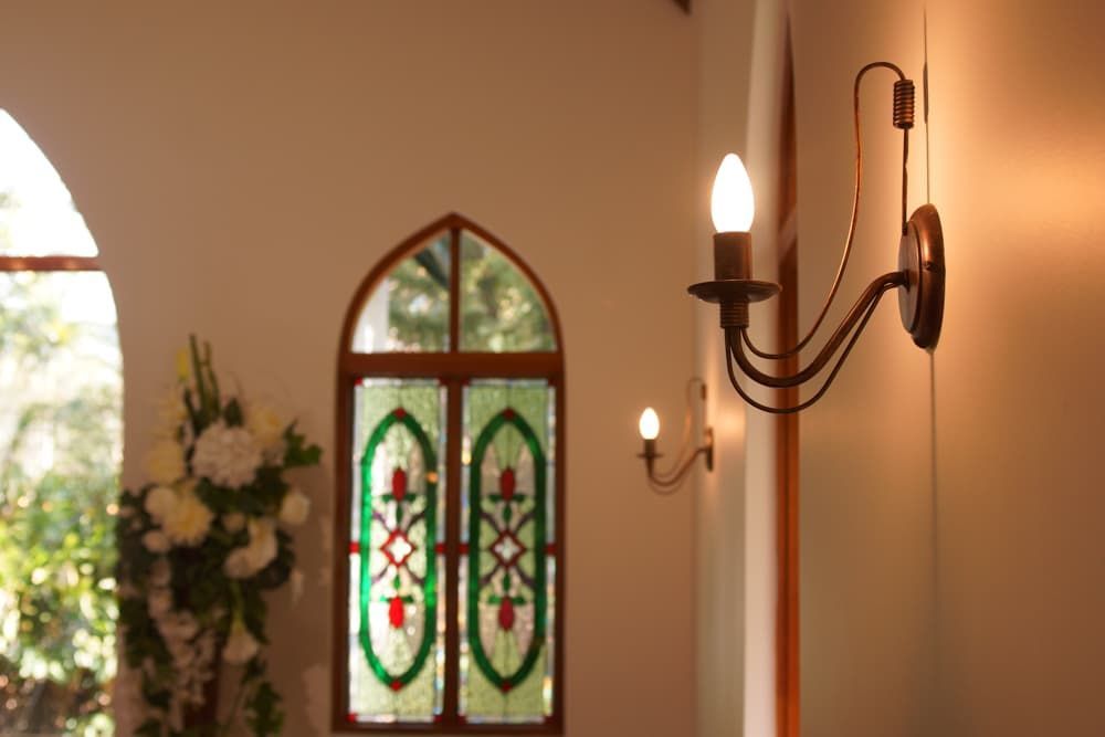 A church with a stained glass window and two candles on the wall - Funeral Services in Upper Coomera, QLD
