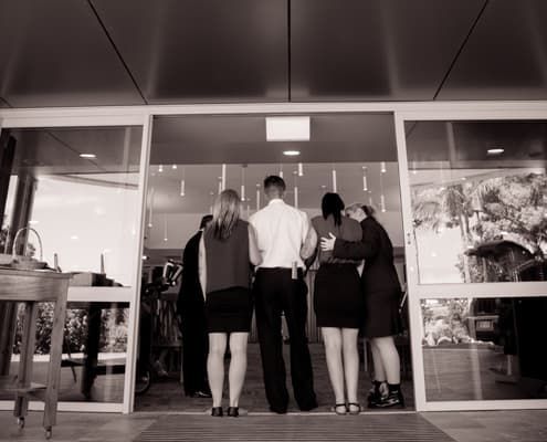 A group of people are standing in a doorway of a building. - Funeral Services in Upper Coomera, QLD