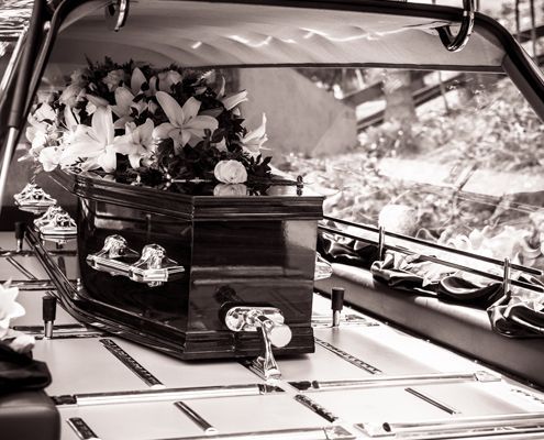 A black and white photo of a coffin in a funeral car - Funeral Services in Upper Coomera, QLD