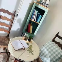 A table with a book on it in a living room next to a bookshelf.