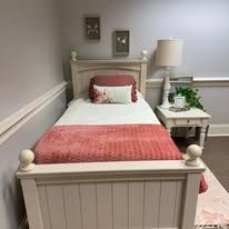 A bedroom with a single bed , nightstand and lamp.