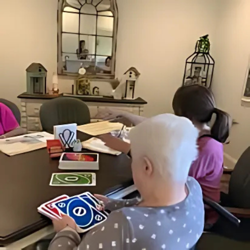 A group of people are sitting around a table playing uno cards