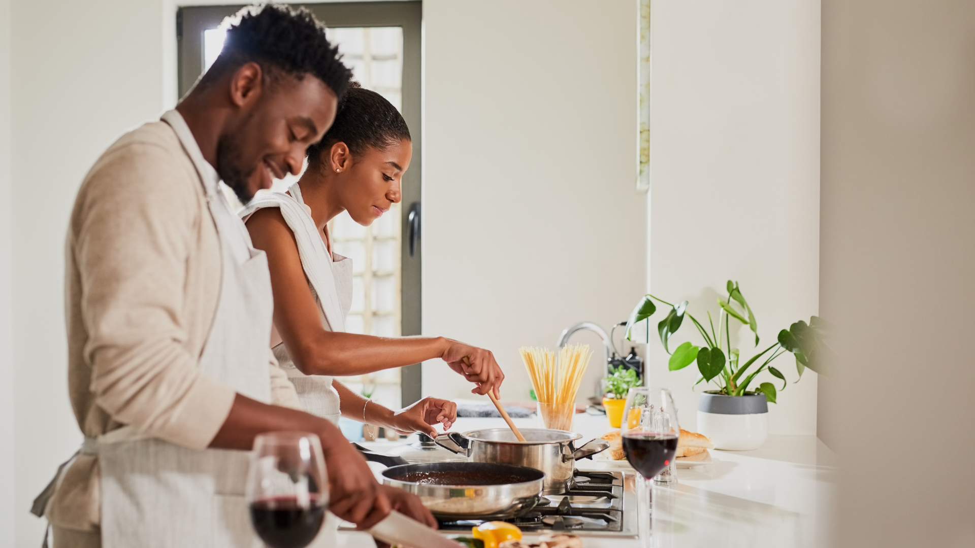 A man and a woman are cooking together in a kitchen.