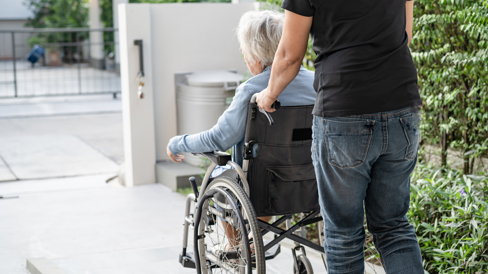 A photo of older woman being pulled on her wheelchair