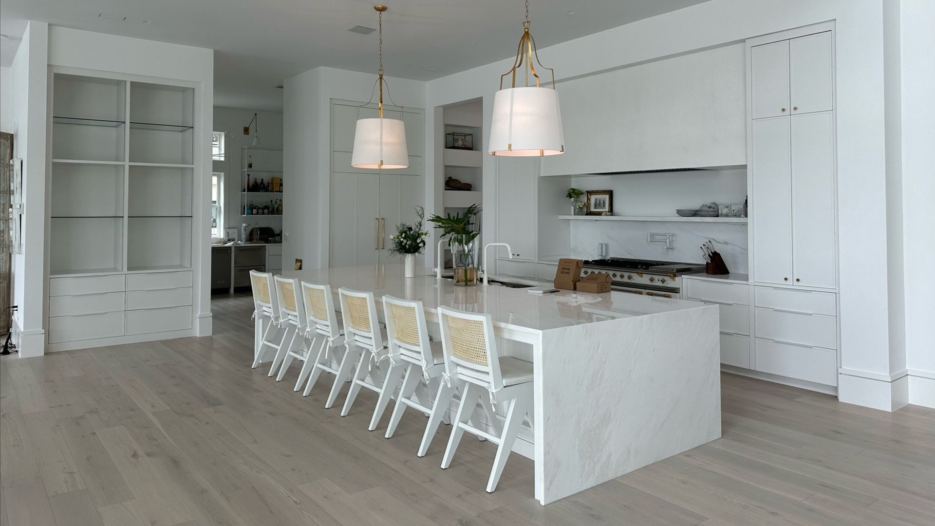 White kitchen with island, pendant lights, and bar stools.