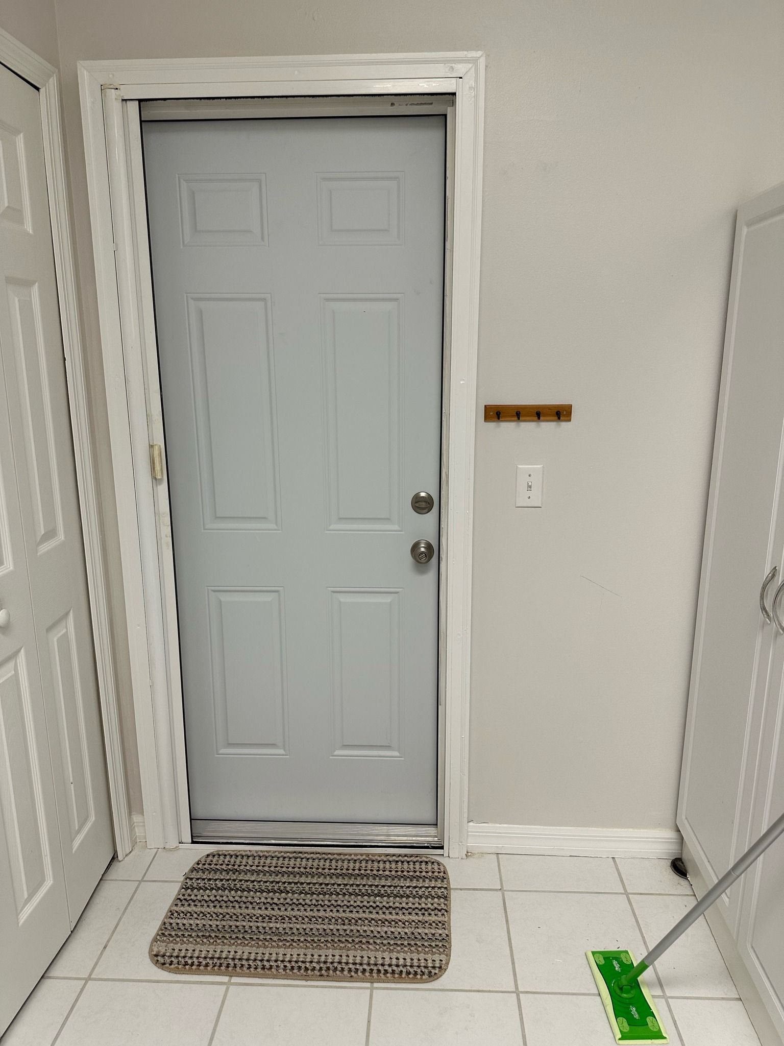 A light blue door with a doormat in a room with white tile flooring.